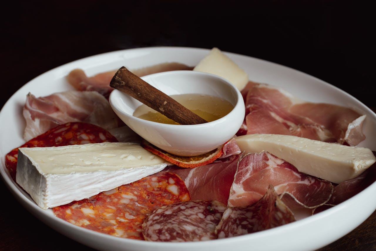 A delicious charcuterie board featuring a variety of meats, cheeses, and honey, perfect for fine dining.